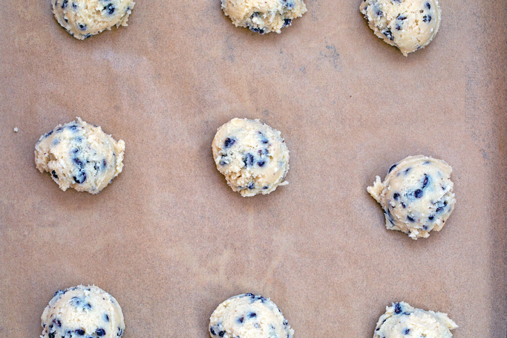 Cookie batter scooped onto parchment paper lined cookie sheet.
