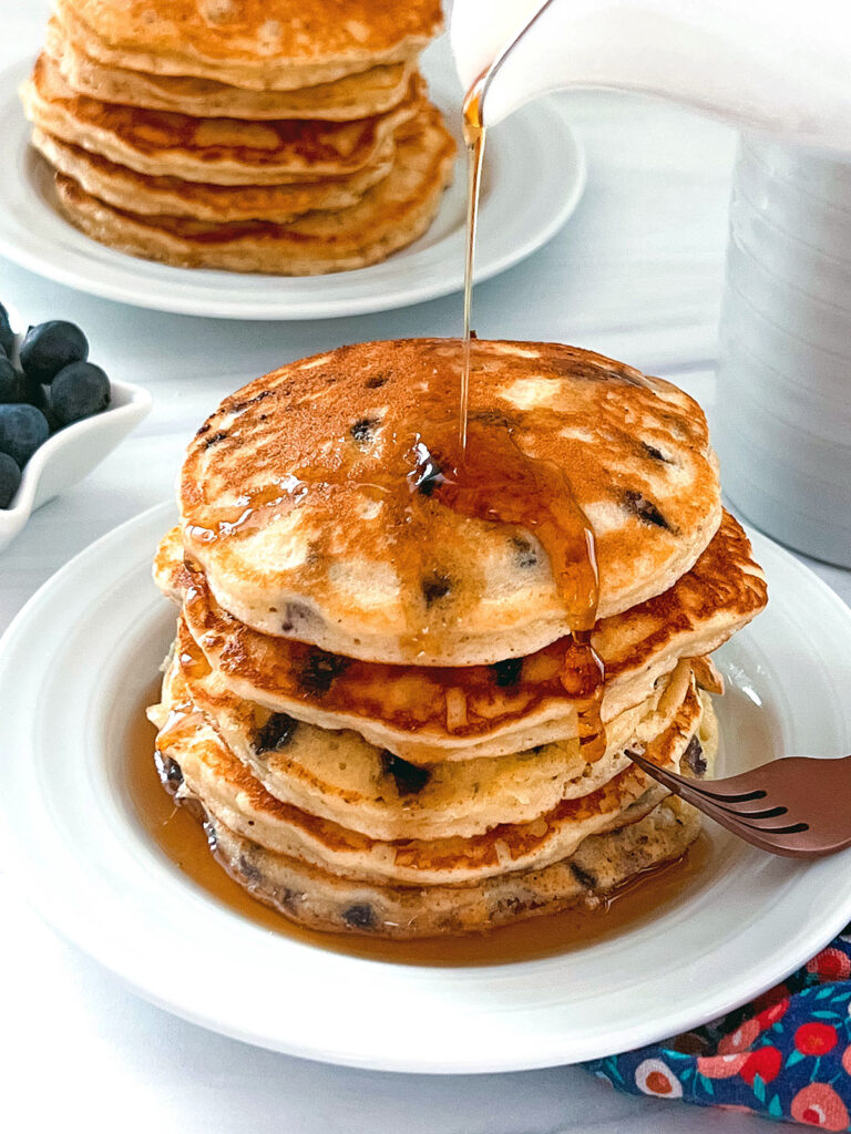 Syrup being poured over a stack of blueberry muffin mix pancakes