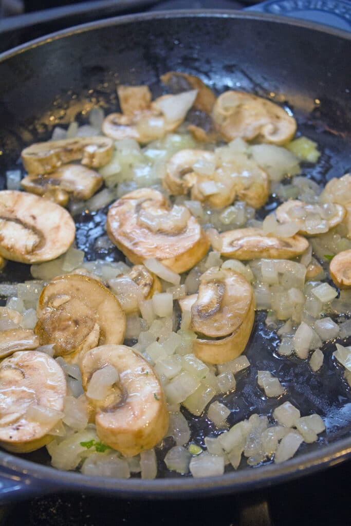 Mushrooms and onions sautéing in skillet.