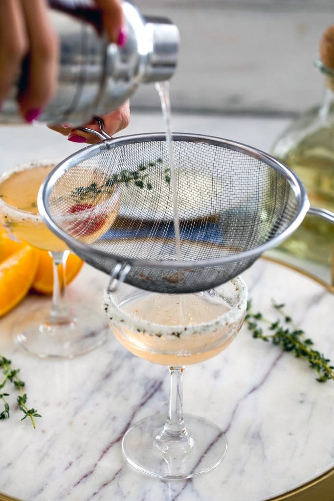 North End Margarita being poured into coup glass with lemon/thyme/pepper citrus salt rim