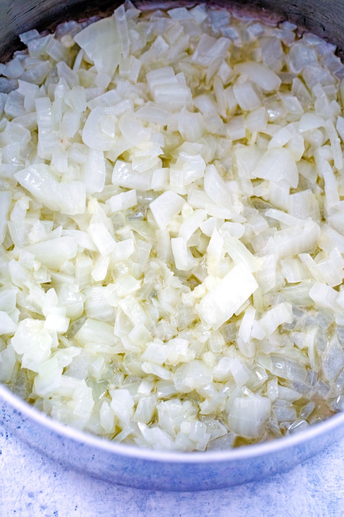 Overhead view of chopped onions being cooked in butter in saucepan
