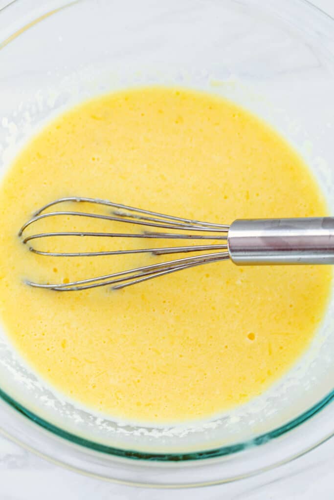Egg, butter, and milk in mixing bowl with whisk.