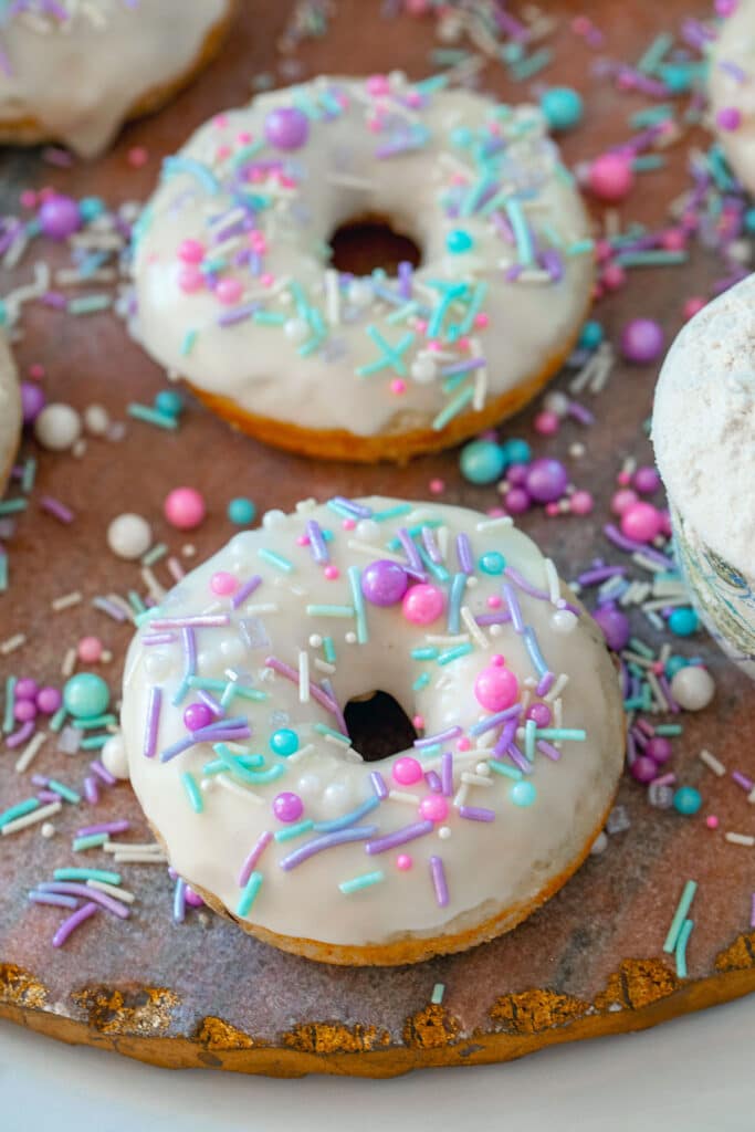 Pancake mix donut with vanilla icing and sprinkles with more donuts in background.
