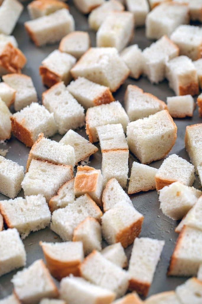 Baking tray with cubed Italian bread covered in olive oil