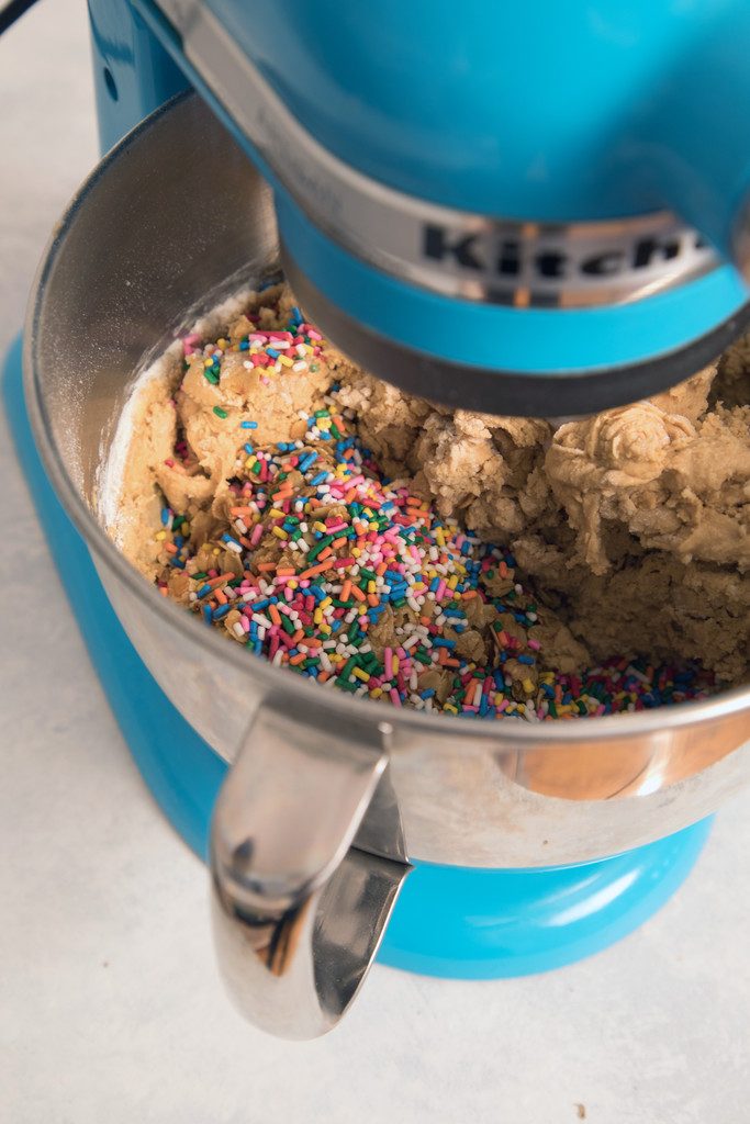Overhead view of blue Kitchenaid mixer with cookie batter with sprinkles in the bowl