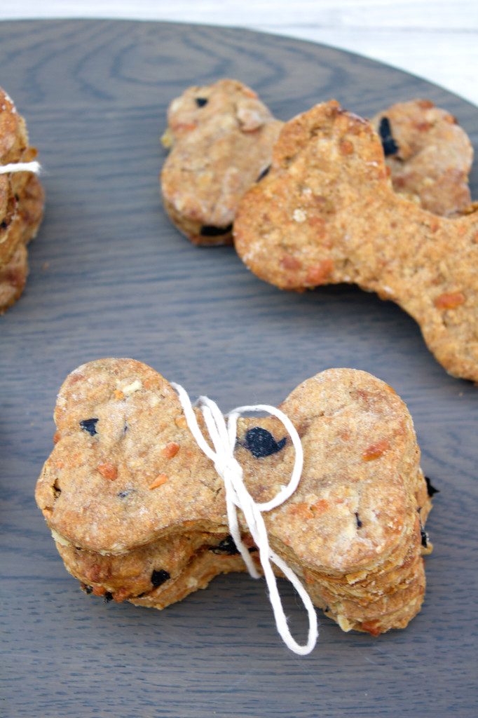 Close-up view of peanut butter cheddar dog bones stacked on a wood tray and tied together with twine