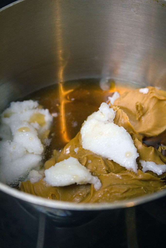 Peanut butter, coconut oil, and maple syrup being combined in saucepan