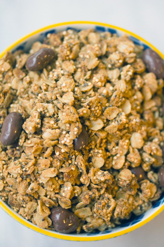 Overhead closeup view of bowl of peanut butter granola with quinoa, chia seeds, and chocolate-covered raisins