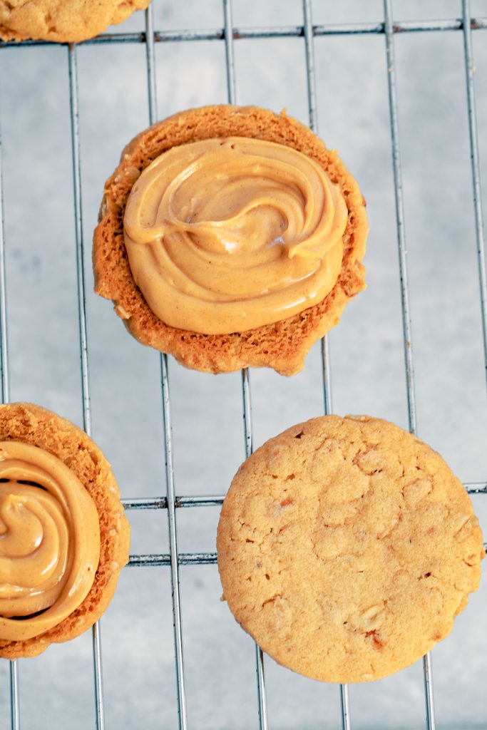 Overhead view of peanut butter cookies on baking rack with some filled with peanut butter cream