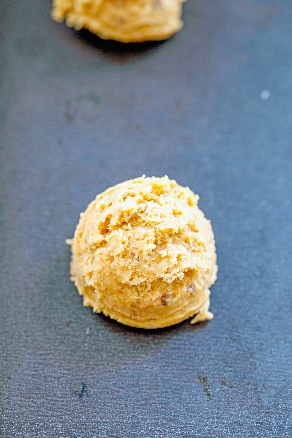 Peanut butter toffee cookie dough ball on baking sheet.