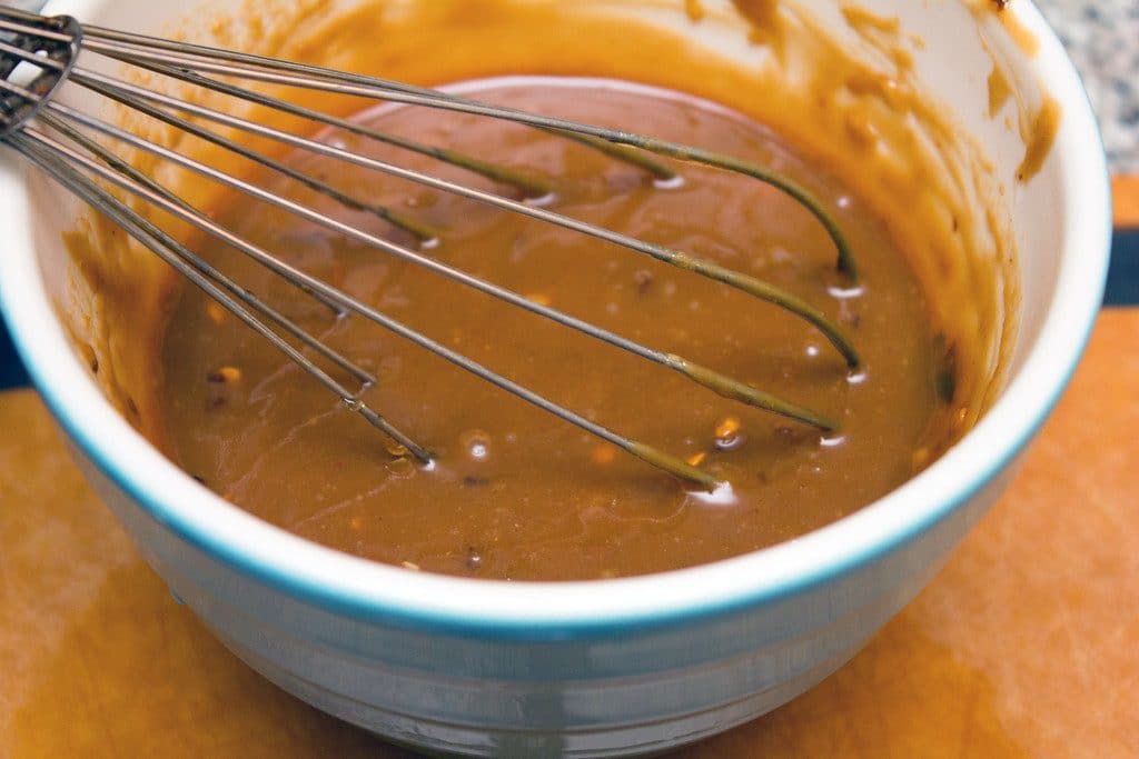 Peanut dressing whisked together in bowl with metal whisk
