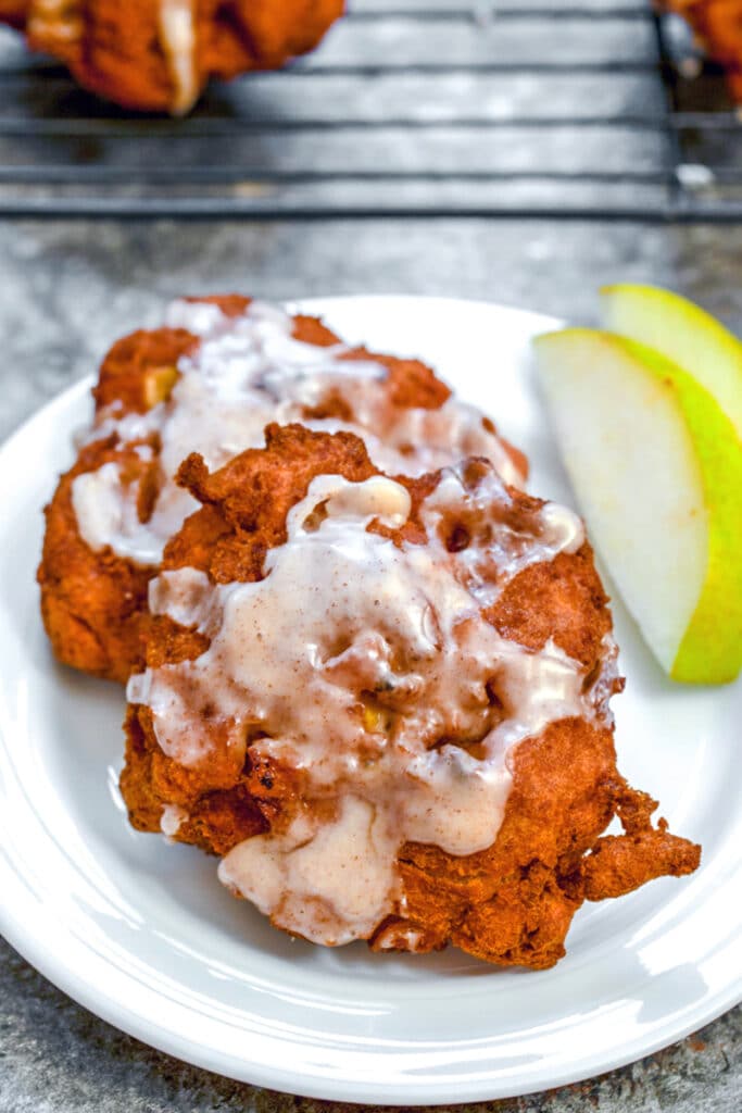 Overhead view of two pear fritters on a white plate with sliced pears