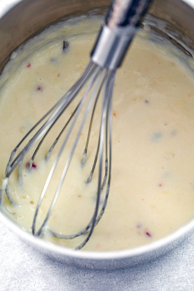 Overhead view of cheese sauce in saucepan with whisk