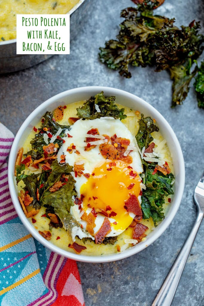 Overhead view of a bowl of pesto polenta topped with kale, bacon, and a runny egg with recipe title at top