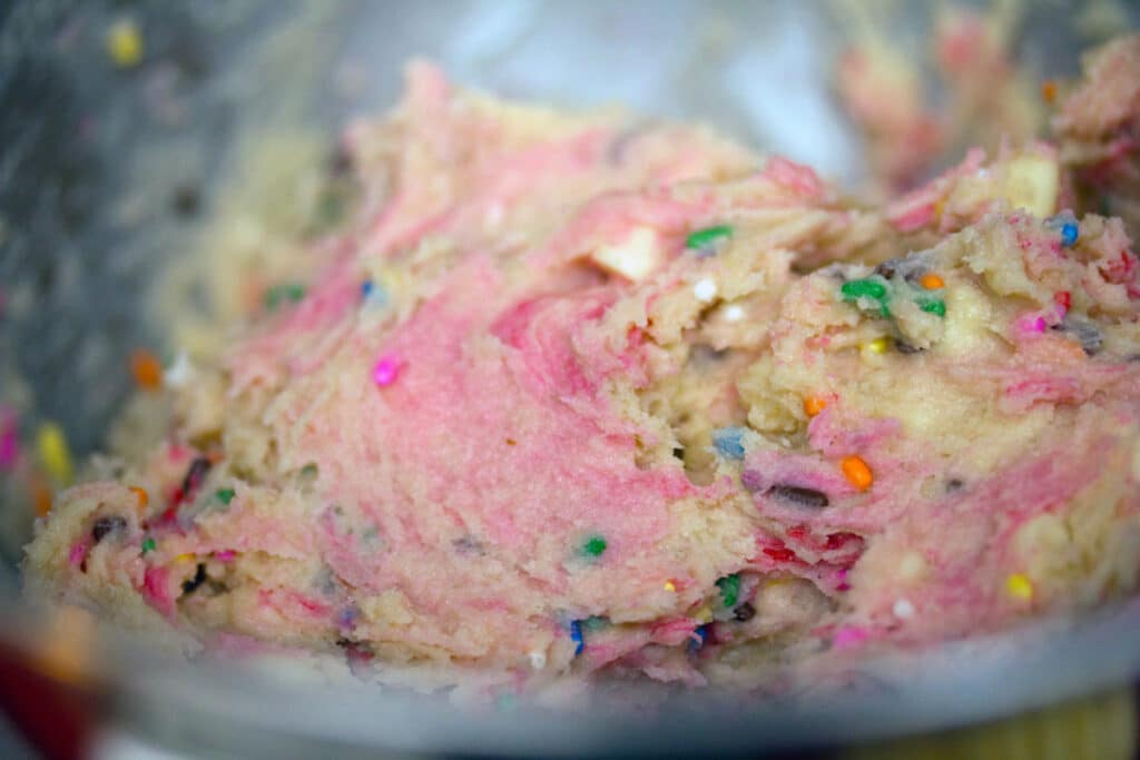 Strawberry milk cookie batter with rainbow sprinkles in mixing bowl