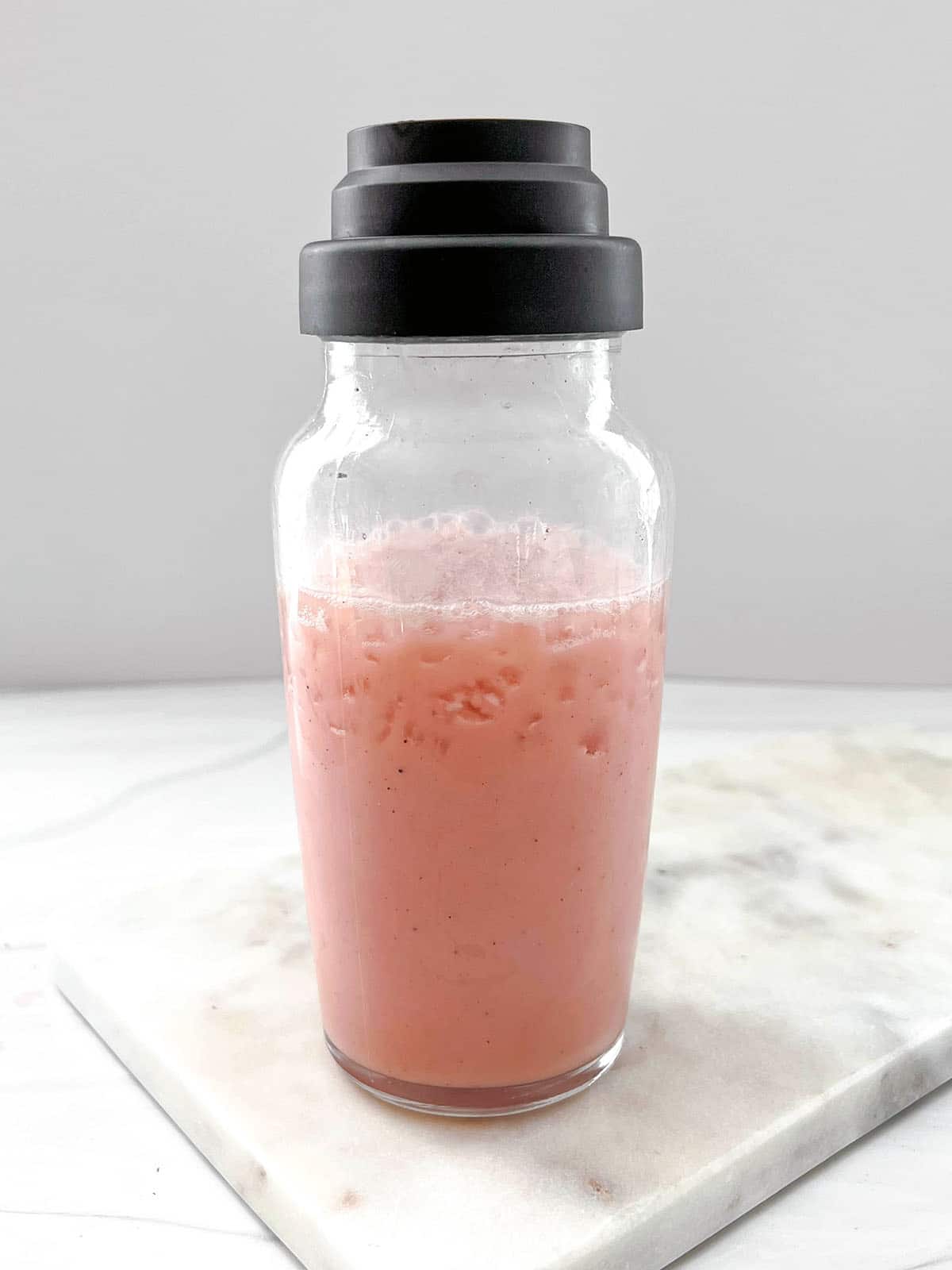Strawberry acai juice and coconut milk in shaker with ice.