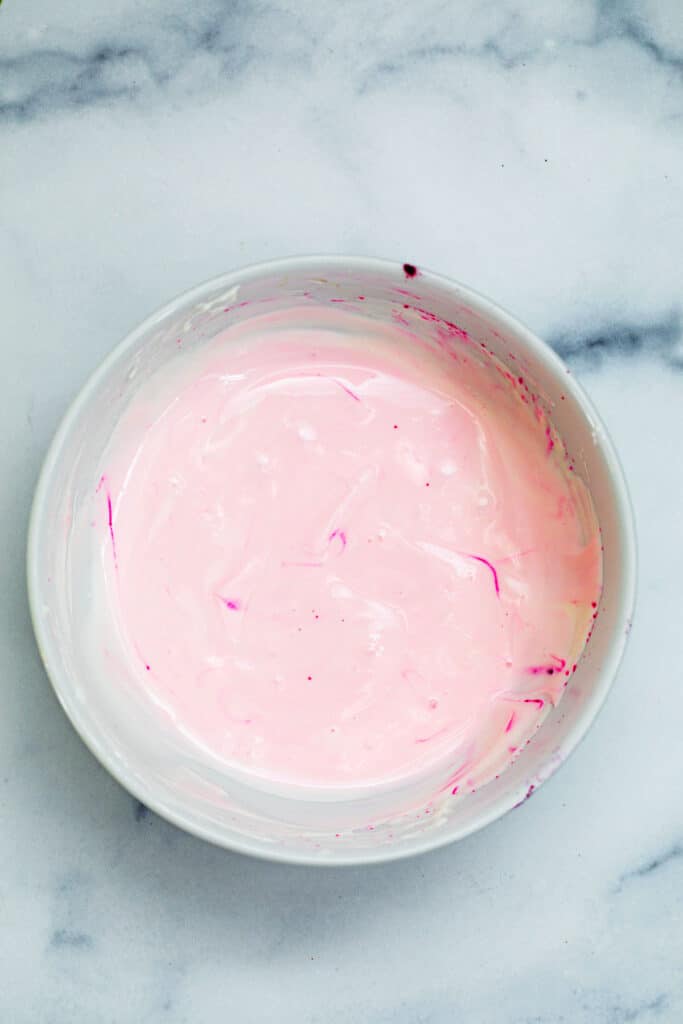 Pink sour cream icing in small bowl