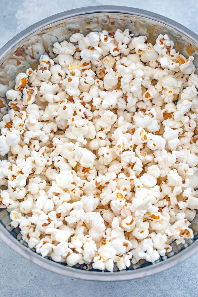 Overhead view of a bowl of popped white popcorn.