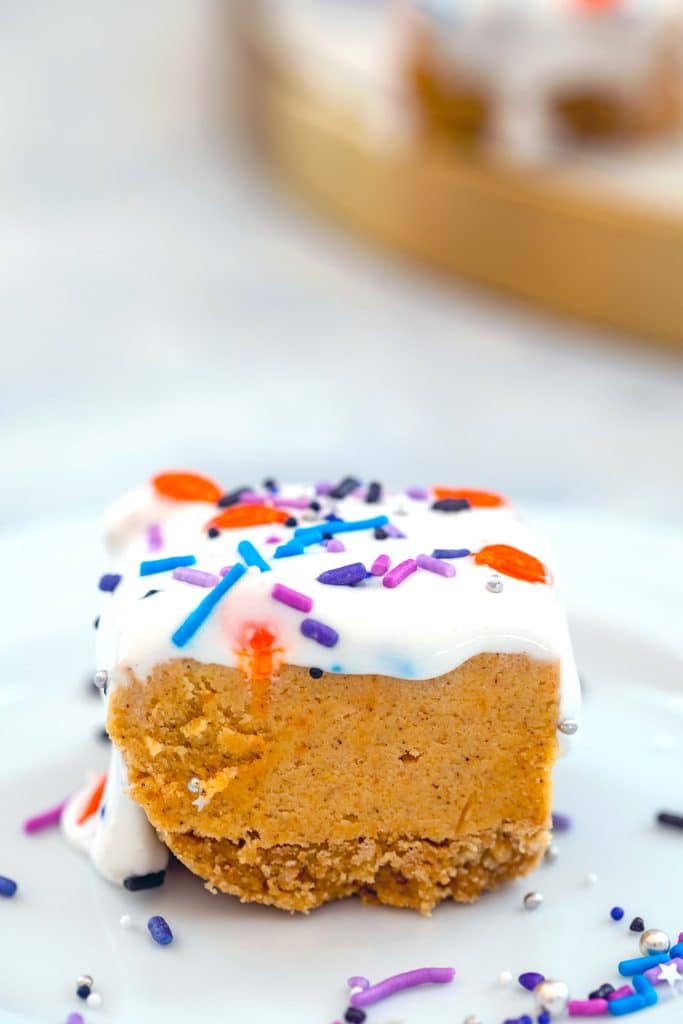 Head-on close-up of a pumpkin cookie dough bar on a white plate with marshmallow topping and sprinkles