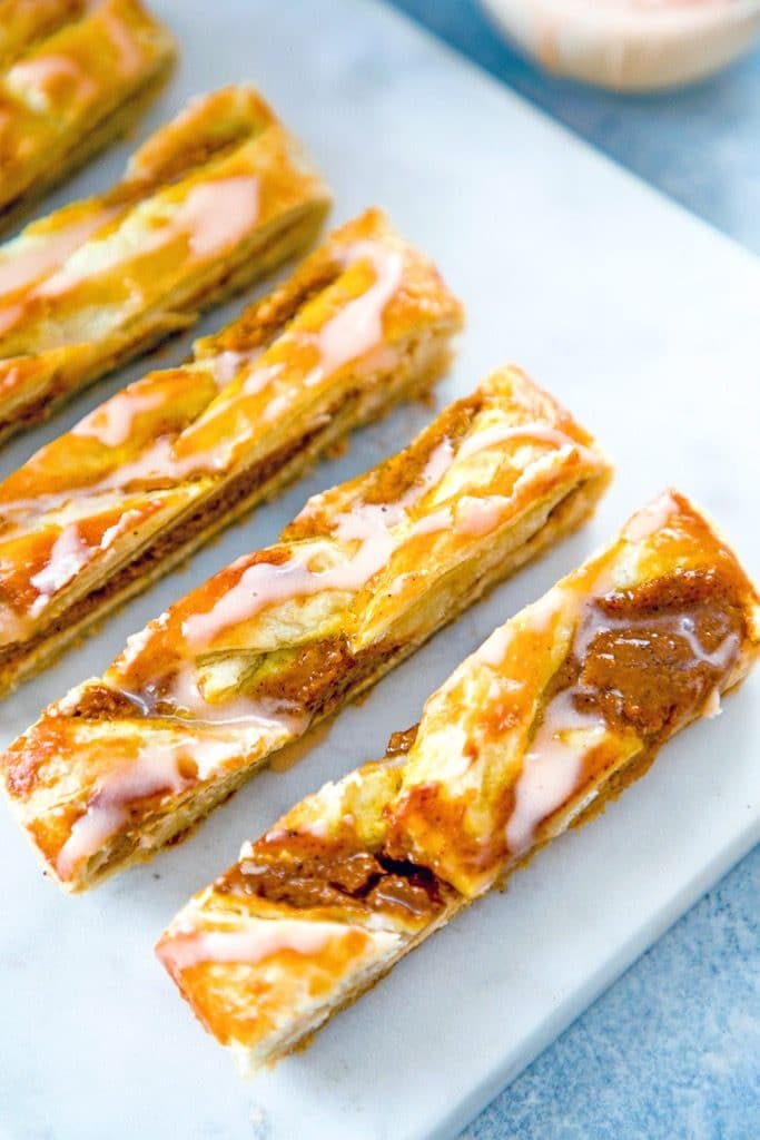 Overhead view of several slices of pumpkin eggnog danish with icing on a marble platter