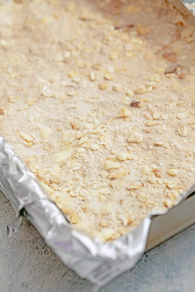 Walnut oat bar crust in a pan with foil overhang