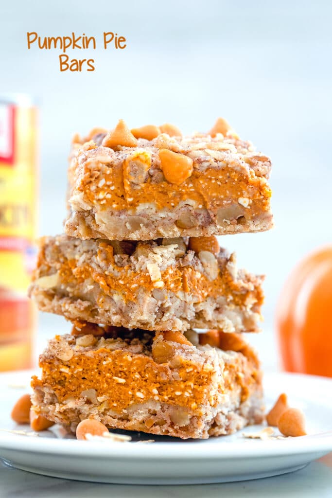 Head-on view of stack of three pumpkin pie bars on a white plate with butterscotch chips and oats on plate and can of pumpkin puree in background with "pumpkin pie bars" text at top