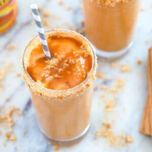 Overhead closeup view of a pumpkin pie milkshake with caramel drizzled over the top and a striped straw