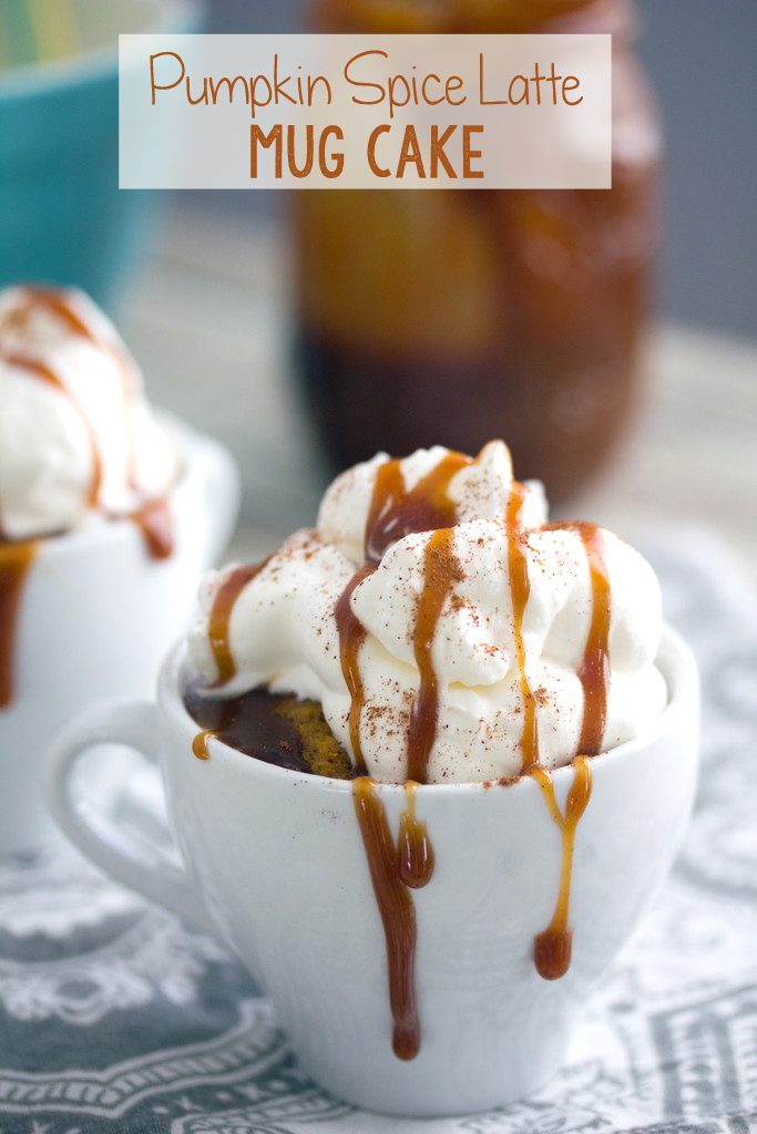 Head-on close-up view of pumpkin spice latte mug cake in a white mug with lots of whipped cream and caramel dripping down sides with second mug cake and jar of caramel in the background and recipe title text at top