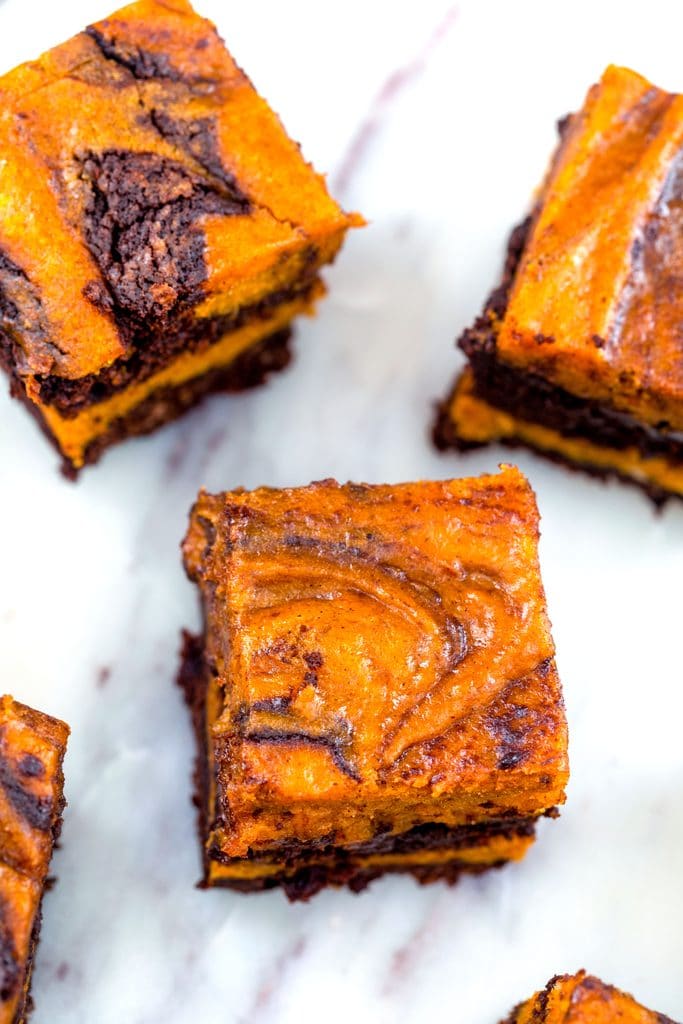 Overhead view of pumpkin swirl brownies with pumpkin and chocolate layers swirled together on a marble surface