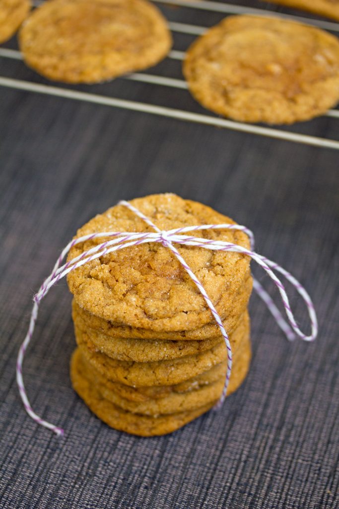 Overhead view of a stack of pumpkin gingersnap cookies tied up with bakers twine with a rack with more cookies in the background