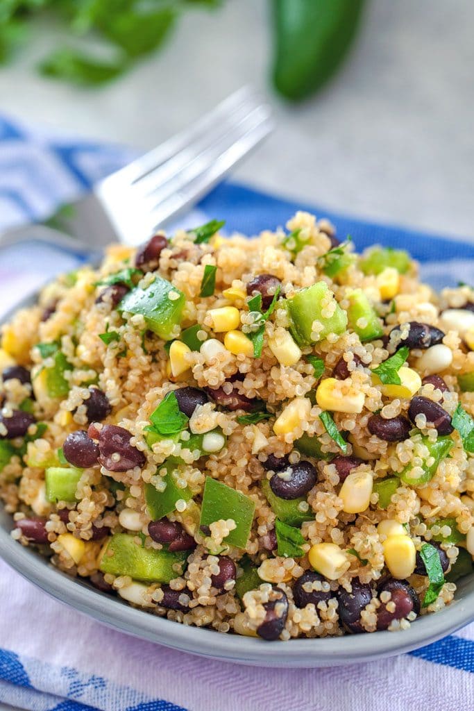 Close-up of quinoa black bean corn salad on a colorful towel with a fork in the background