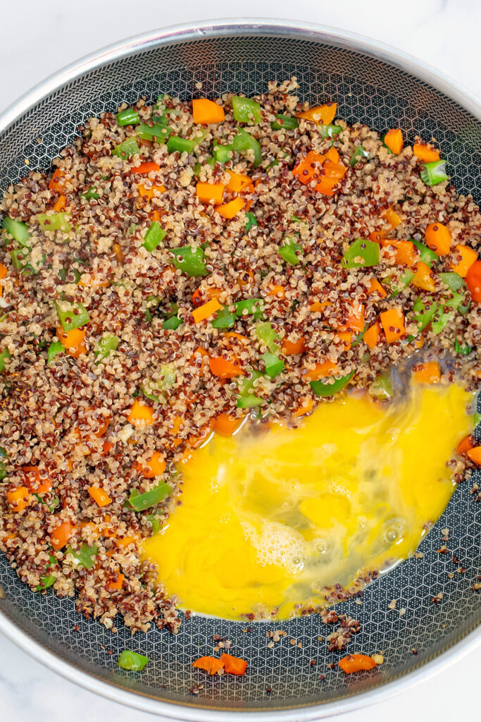 Overhead view of wok with quinoa and vegetables on one side and egg on the other side