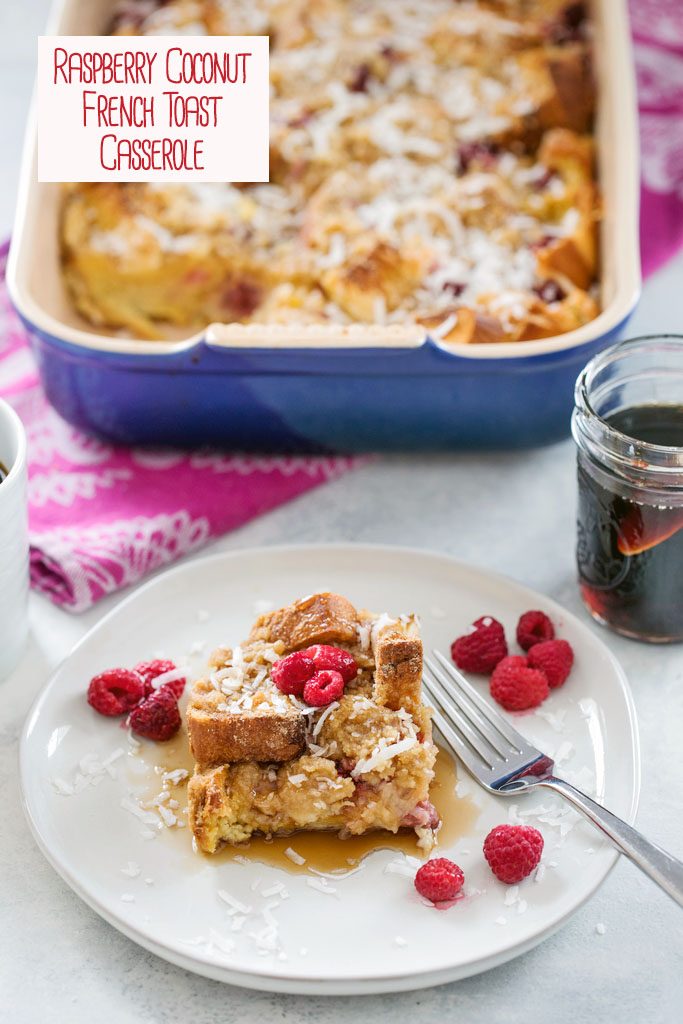 Overhead view of a plate with a serving of raspberry coconut french toast casserole with the baking dish in the background, along with a jar of maple syrup with recipe title at top