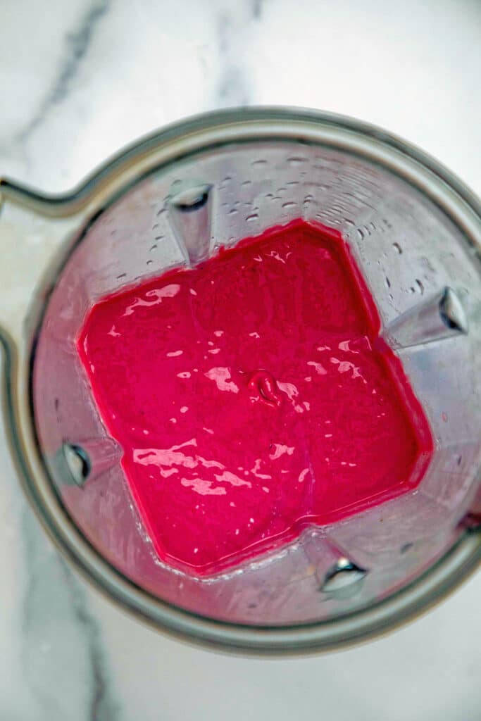 Overhead view of raspberry jelly layer of smoothie in blender