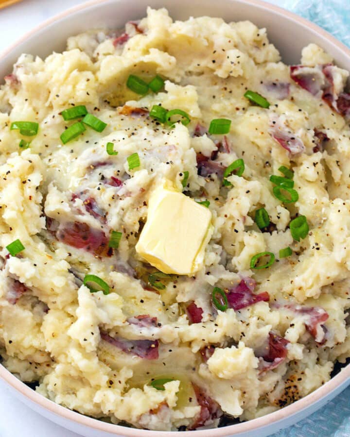 Closeup view of red skin mashed potatoes with scallions and a pat of butter on top.
