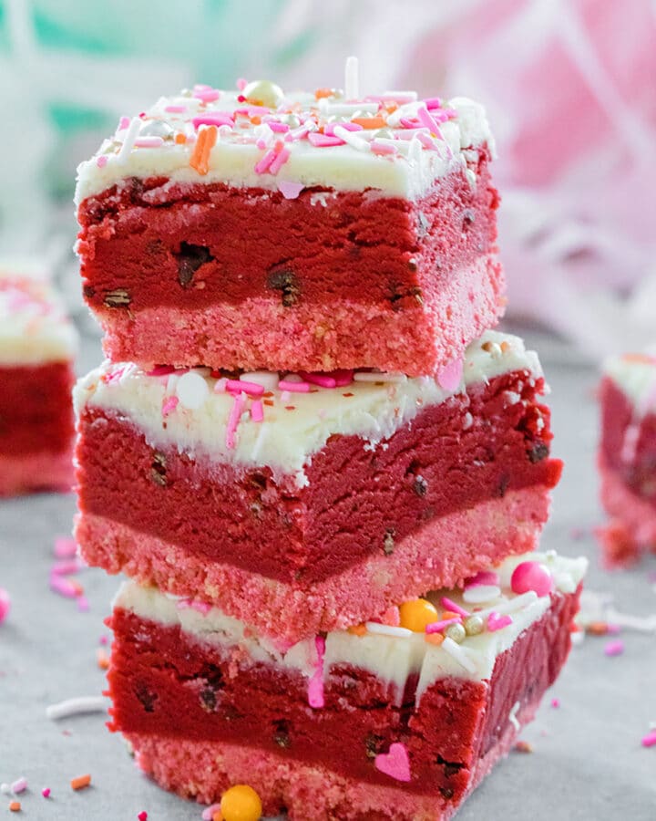 Stack of three red velvet cookie dough bars with sprinkles