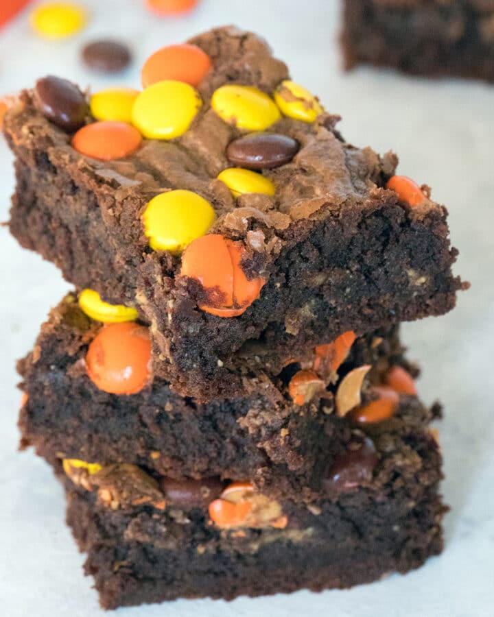 Stack of Reese's Pieces peanut butter brownies with Reese's Pieces candy in background
