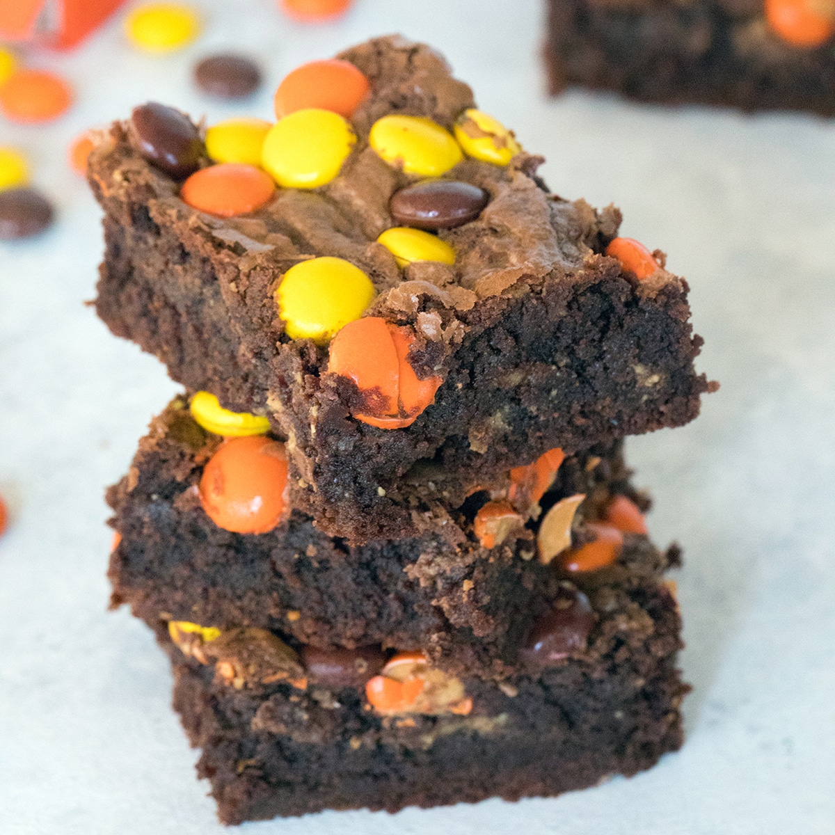 Stack of Reese's Pieces peanut butter brownies with Reese's Pieces candy in background