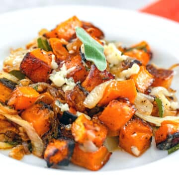 Closeup view of cubed roasted butternut squash with caramelized onions, gorgonzola, and sage.