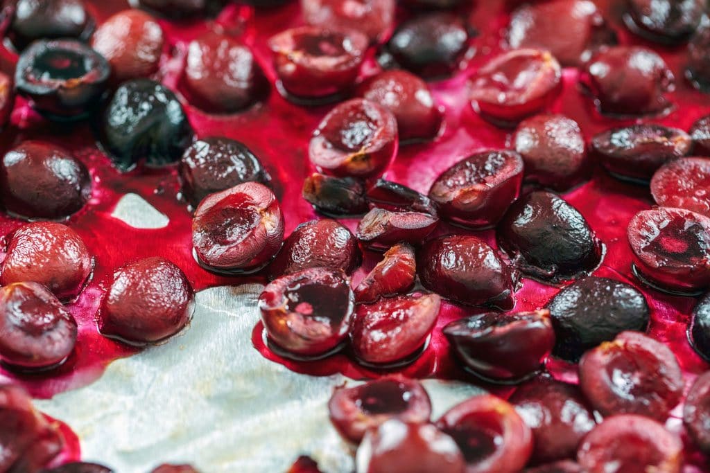 Roasted cherries cut in half in pan after coming out of oven