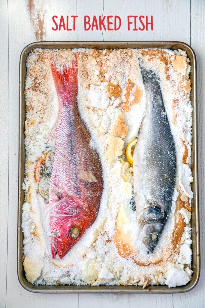 Overhead view of two fish whole on a baking pan with salt chipped away and recipe title at the top.