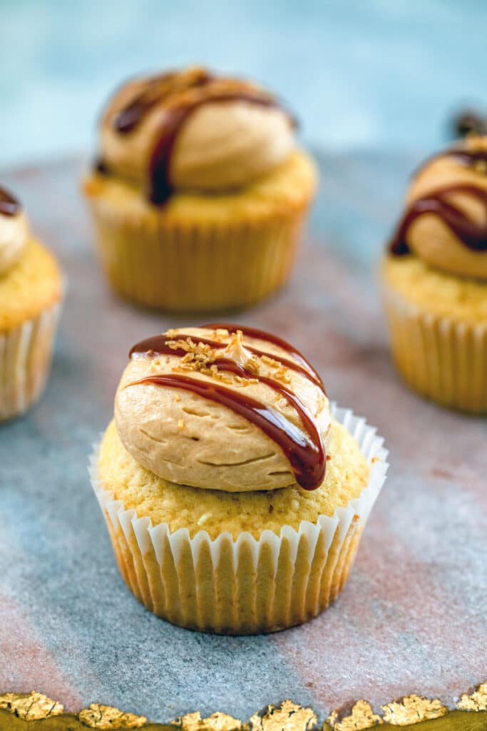 Head-on view of a salted caramel cupcake with caramel drizzle with more cupcakes in background