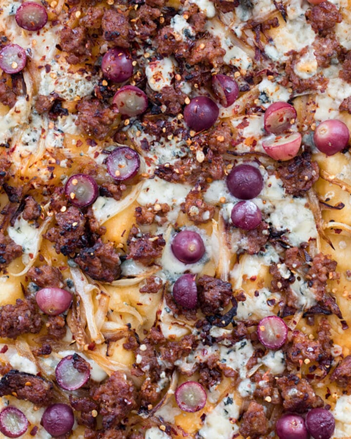 Sausage, Grape, and Gorgonzola Flatbread Pizza -- A seemingly unlikely combination, the flavors in this flatbread pizza work so well together, you'll find yourself craving this ultra thin crust pizza all the time | wearenotmartha.com #flatbread #pizza #sausage #gorgonzola #appetizer