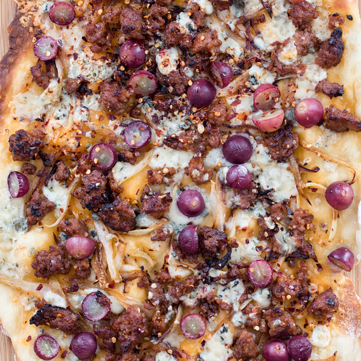 Sausage, Grape, and Gorgonzola Flatbread Pizza -- A seemingly unlikely combination, the flavors in this flatbread pizza work so well together, you'll find yourself craving this ultra thin crust pizza all the time | wearenotmartha.com #flatbread #pizza #sausage #gorgonzola #appetizer