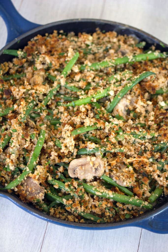 Close-up overhead view of skillet green beans with mushrooms and breadcrumb topping in a blue skillet