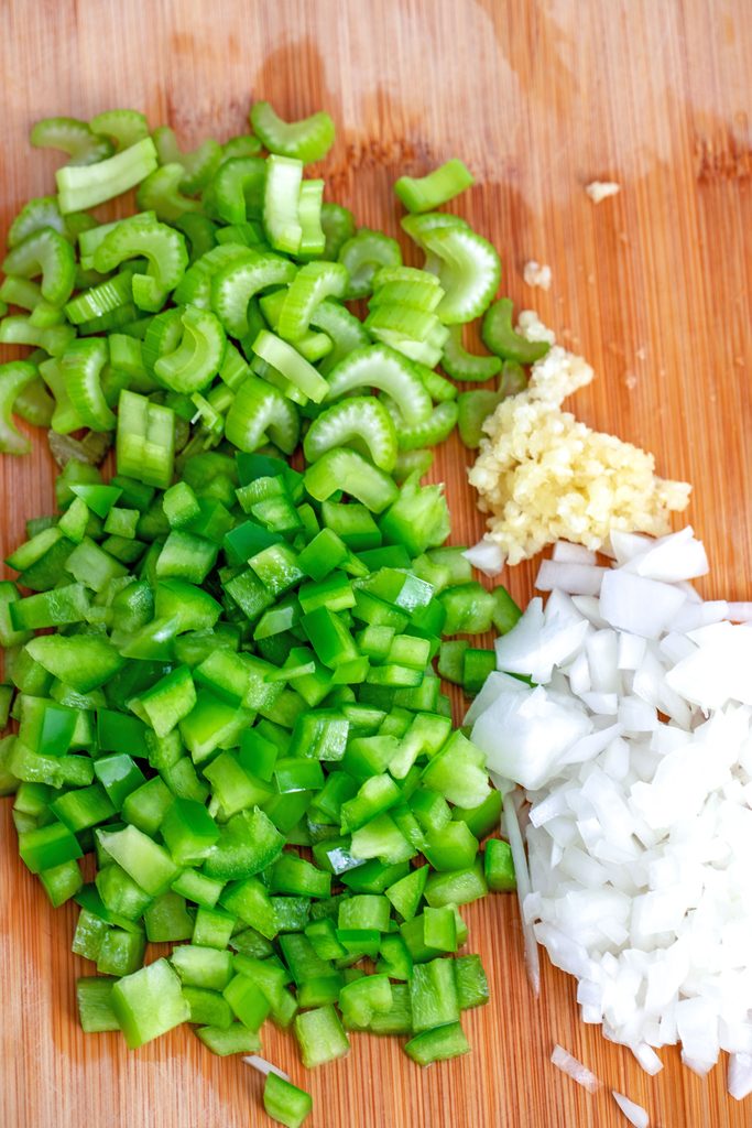 Overhead view of chopped peppers, celery, onions, and garlic on cutting board