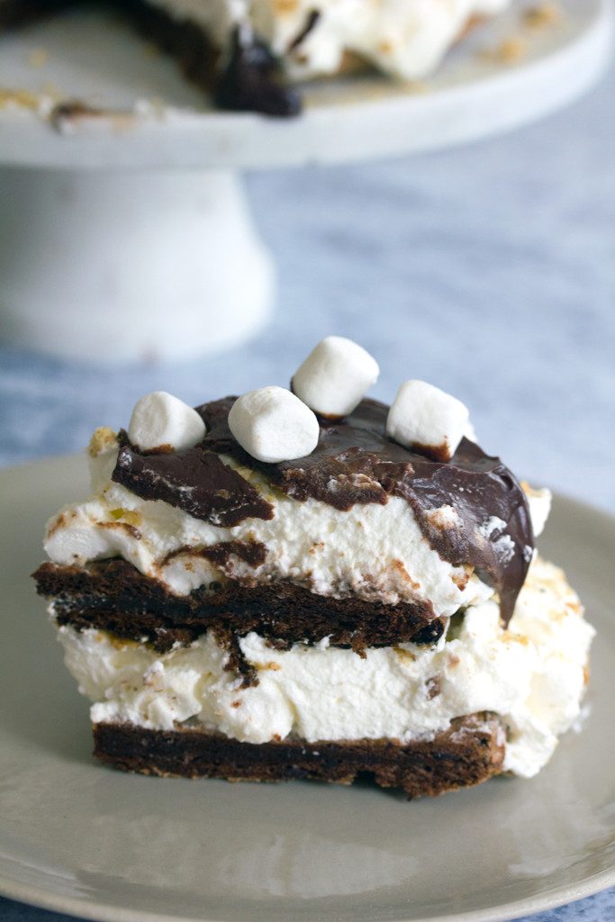 Overhead view of a slice of s'mores pavlova cake with marshmallow shipped cream filling, chocolate ganache, and mini marshmallows