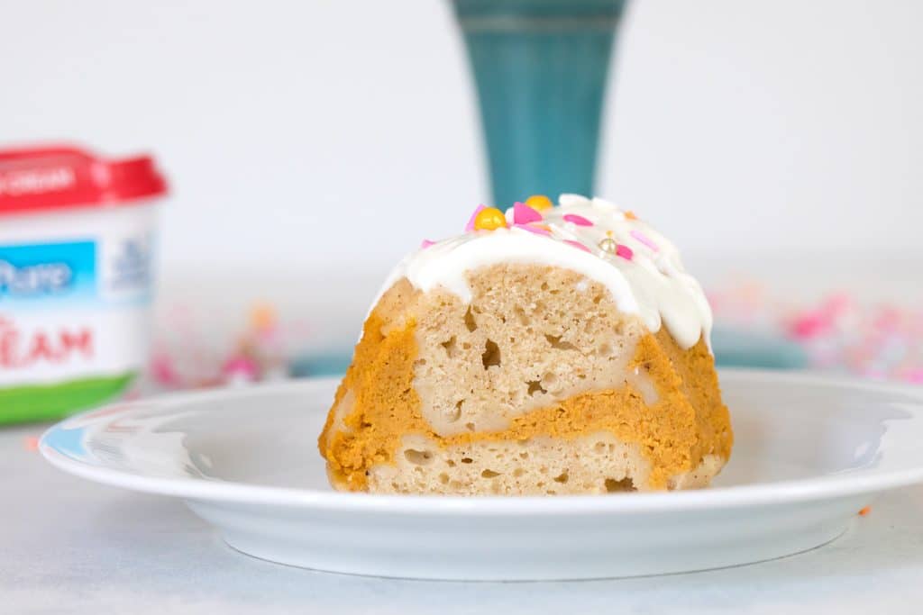 Head-on landscape view of a slice of sour cream pumpkin pie bundt cake on a white plate