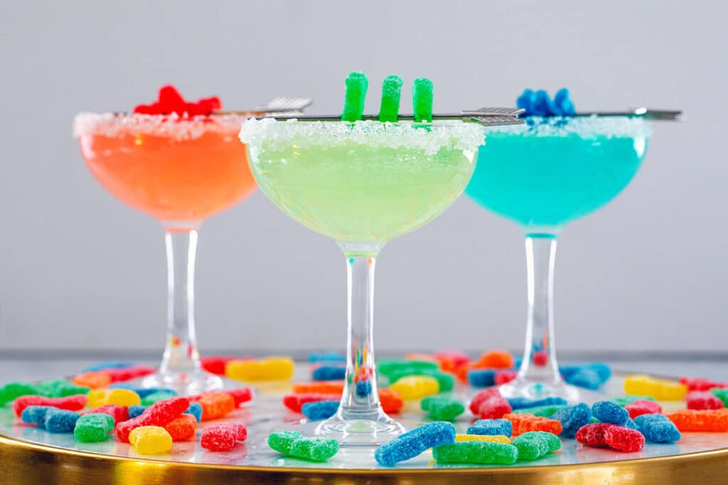 Landscape head-on view of three Sour Patch Kids Margaritas with candies all around