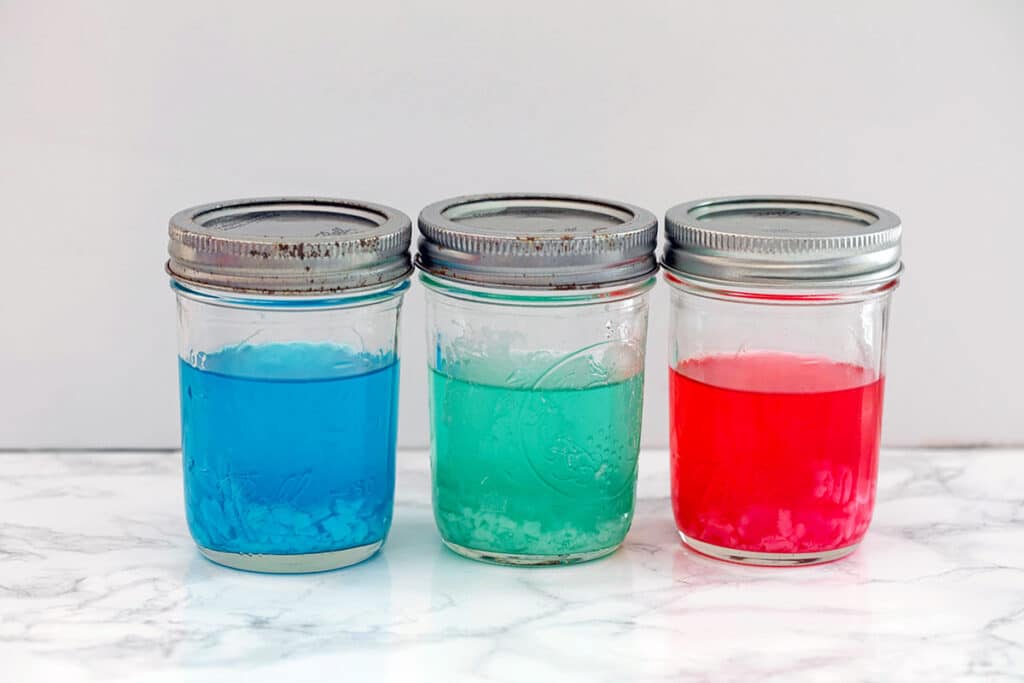 Blue, green, and red jars of Sour Patch Kids infused tequila